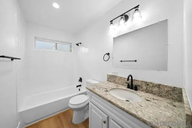 a bathroom with a granite countertop sink a toilet and bathtub