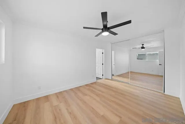 a view of empty room with wooden floor and ceiling fan