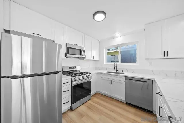 a kitchen with a sink appliances cabinets and a counter top space