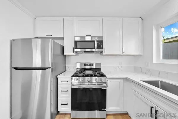 a kitchen with stainless steel appliances white cabinets and a refrigerator