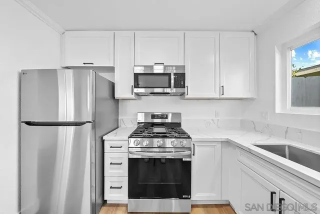 a kitchen with stainless steel appliances white cabinets and a refrigerator