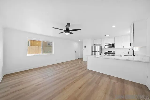 a view of a kitchen with wooden floor a sink and a window