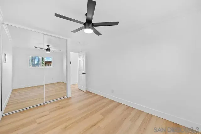 a view of empty room with wooden floor and window