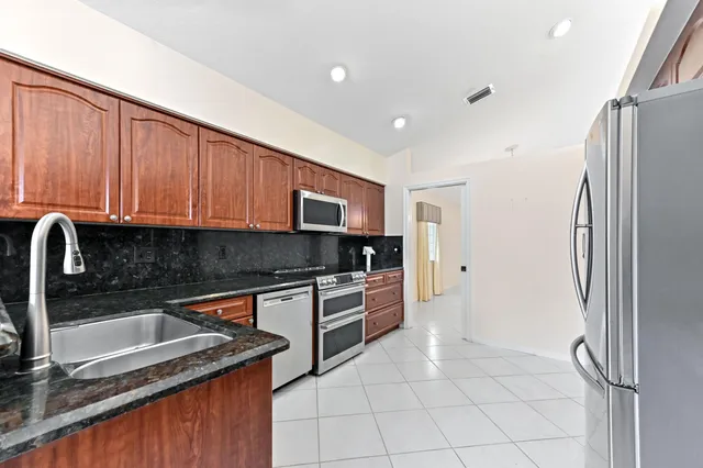 a kitchen with stainless steel appliances granite countertop a refrigerator and a sink