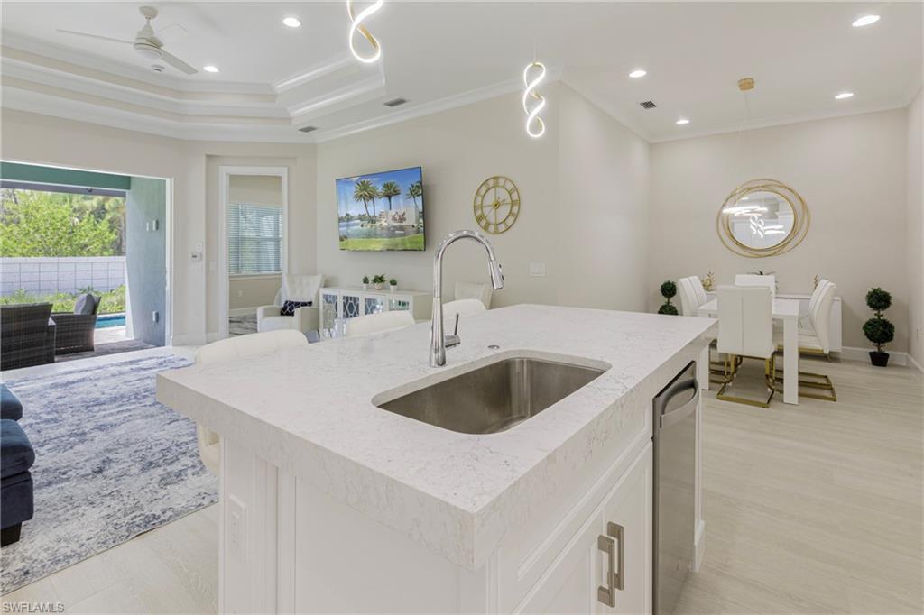 8909 Yucatan Court Naples, FL 34113 - Photo 35 of 36 Kitchen with open floor plan, recessed lighting, ornamental molding, hanging light fixtures, and light stone counters