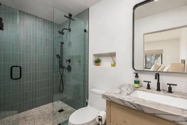 a bathroom with a granite countertop sink toilet a mirror and shower