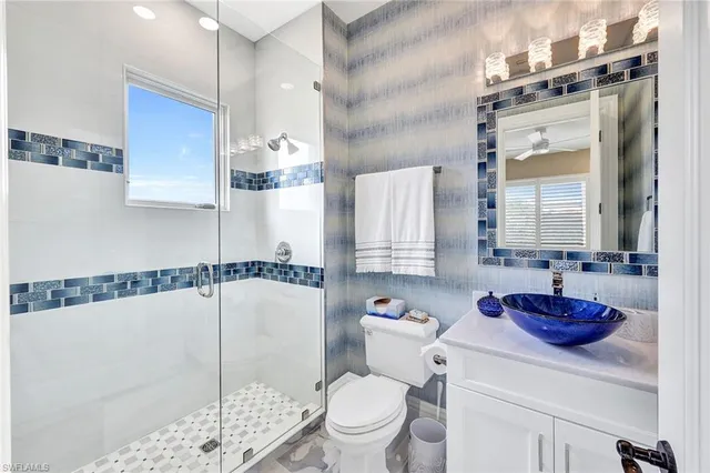 a bathroom with a granite countertop sink a toilet and shower
