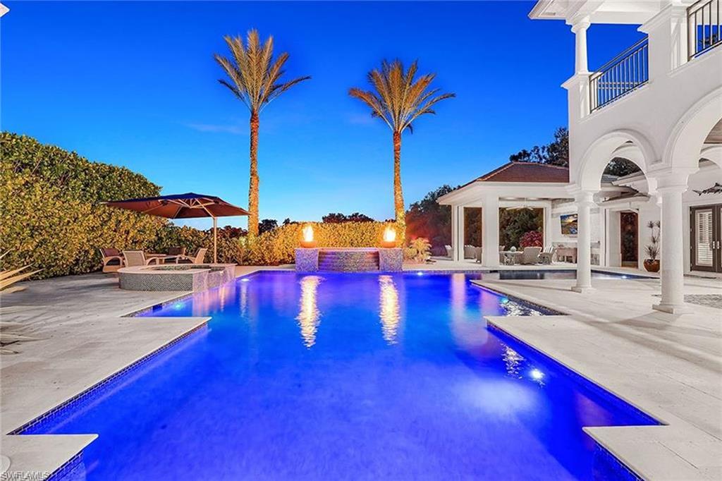 16770 Prato Way Naples, FL 34110 - Photo 26 of 29 a view of a swimming pool with lawn chairs under an umbrella