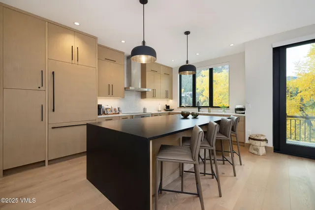 a kitchen with stainless steel appliances granite countertop a sink a stove a refrigerator and island with wooden floor