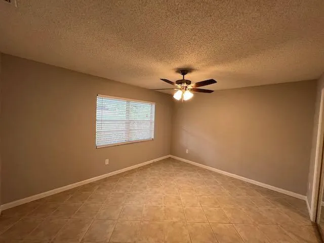 an empty room with a window and a ceiling fan