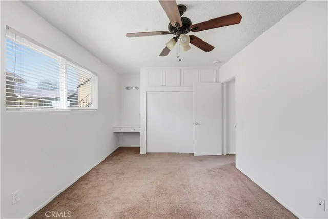 an empty room with a ceiling fan and window