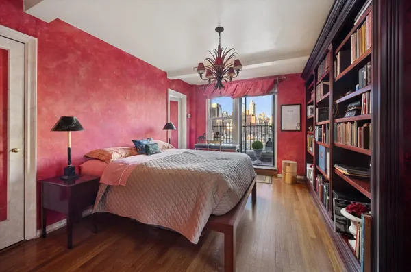 a bedroom with a bed a mirror on dresser and a flat screen tv