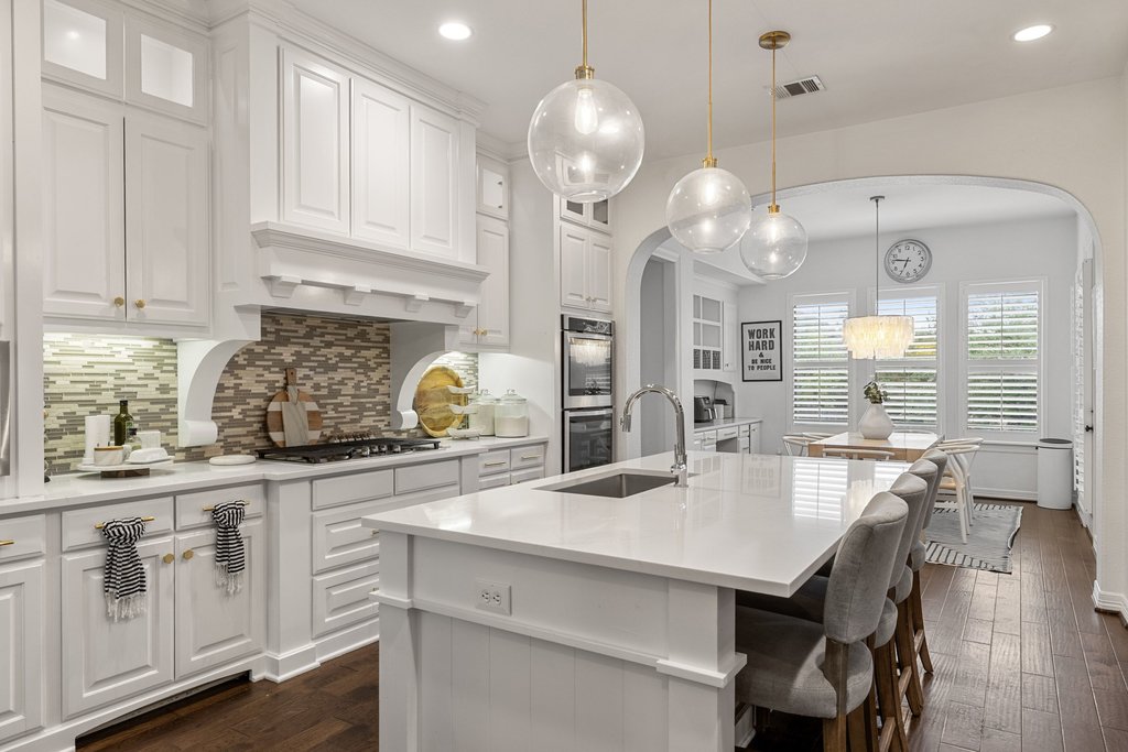 8801 Wild Rice Cove Austin, TX 78738 - Photo 12 of 40 a kitchen with white cabinets and chandelier