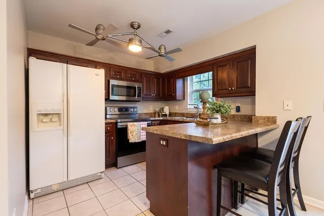 a kitchen with stainless steel appliances granite countertop a refrigerator a sink dishwasher a stove with a dining table and chairs