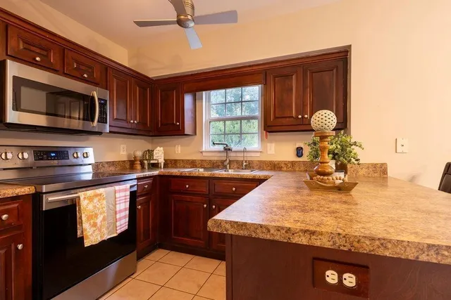 a kitchen with stainless steel appliances granite countertop a sink dishwasher stove and microwave with wooden cabinets