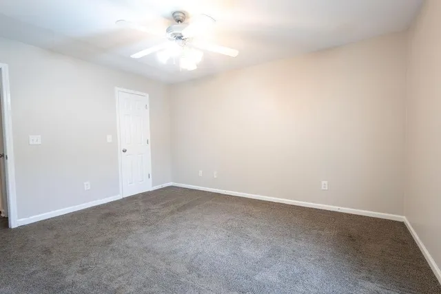an empty room with a fan & a ceiling fan