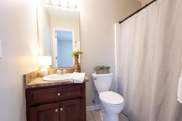 a bathroom with a granite countertop toilet sink and mirror