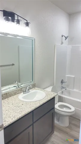 a bathroom with a granite countertop sink a toilet and a large mirror