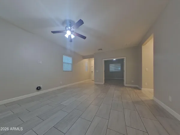 a view of an empty room with wooden floor and a chandelier fan