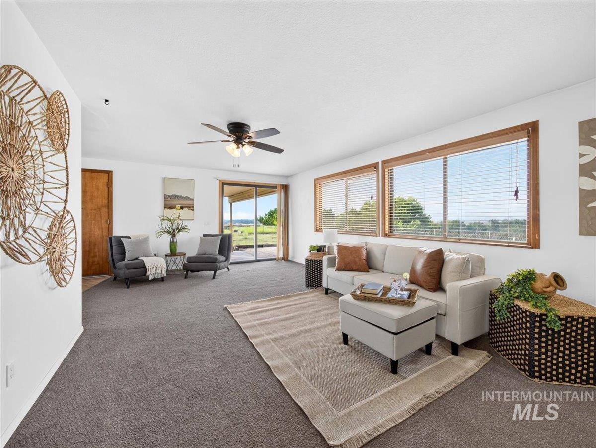 8989 Hillview Road Emmett, ID 83617 - Photo 8 of 50 Living area featuring abundant natural light, carpeted flooring, a ceiling fan, and extensive outdoor scenery through large windows and a sliding glass door