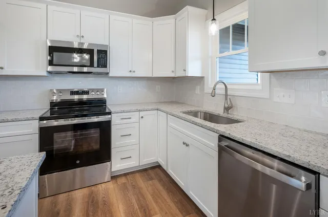 a large kitchen with granite countertop a large counter top space a sink appliances and cabinets