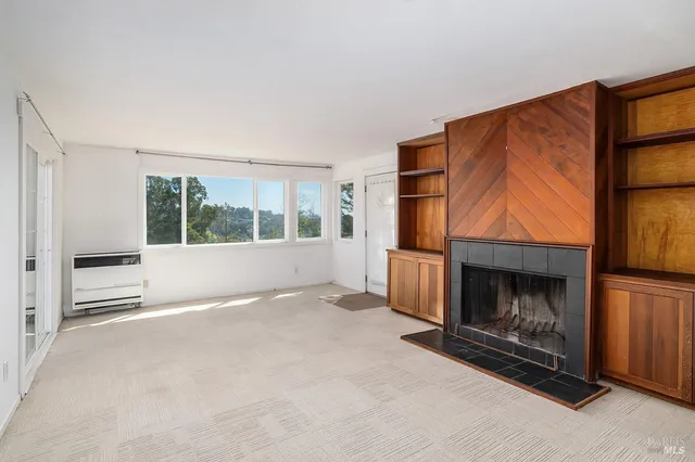 a view of an empty room with a fireplace and a window