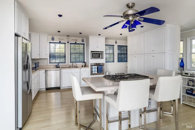 a kitchen with stainless steel appliances kitchen island granite countertop a table chairs and white cabinets