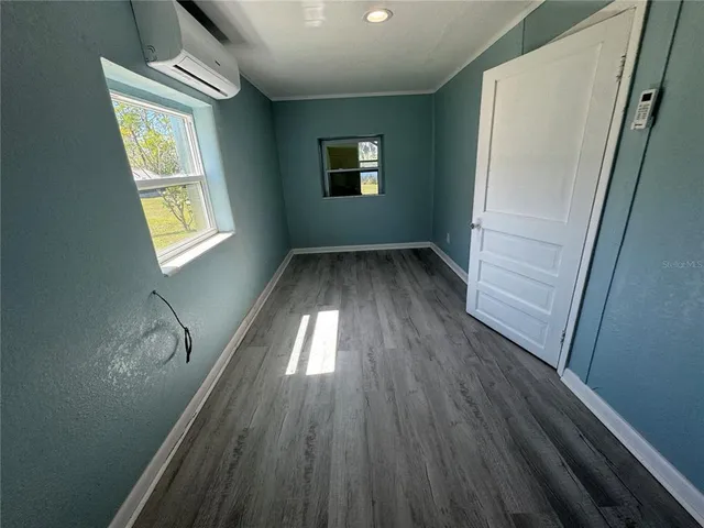 a view of hallway with window and wooden floor