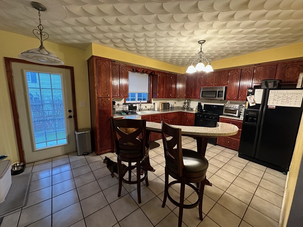166 Bradford Avenue Fall River, MA 02721 - Photo 19 of 28 a kitchen with stainless steel appliances a sink a stove a refrigerator cabinets and dining table