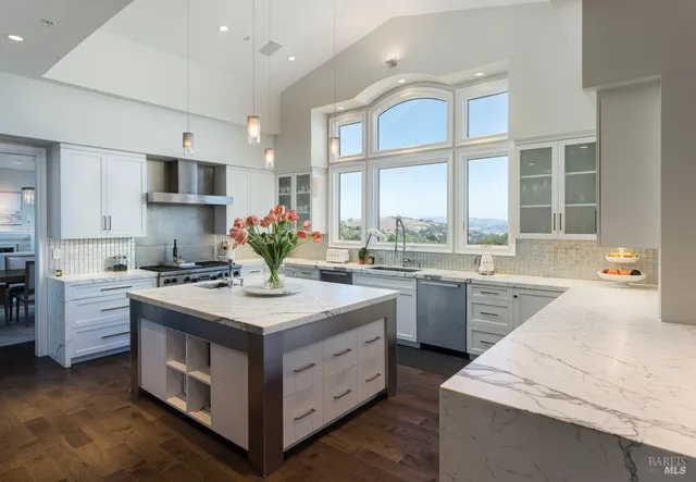 a kitchen with stainless steel appliances kitchen island granite countertop a refrigerator a sink dishwasher with a dining table and chairs