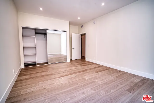 a view of an empty room with wooden floor and closet