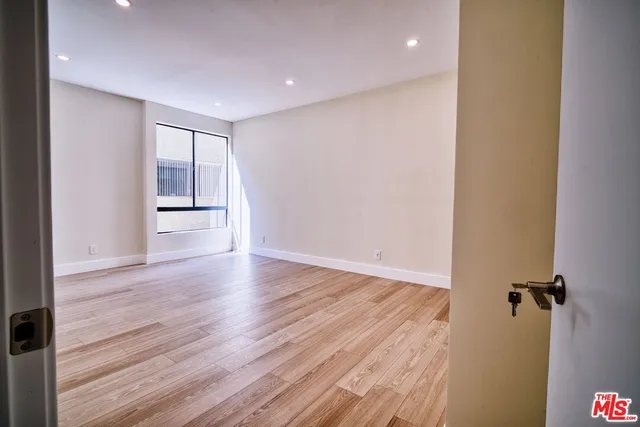 a view of an empty room with wooden floor and closet