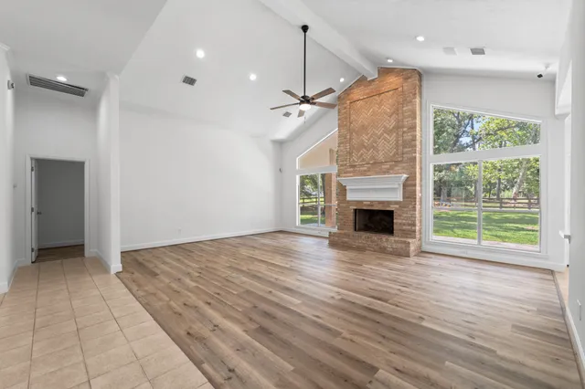 a view of an empty room with wooden floor fireplace and a window