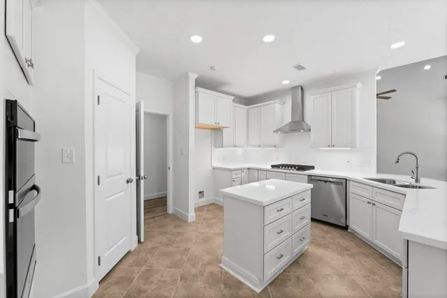 a large kitchen with kitchen island a sink a refrigerator and white cabinets