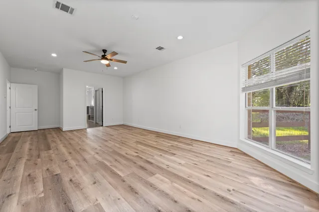 a view of empty room with wooden floor and fan