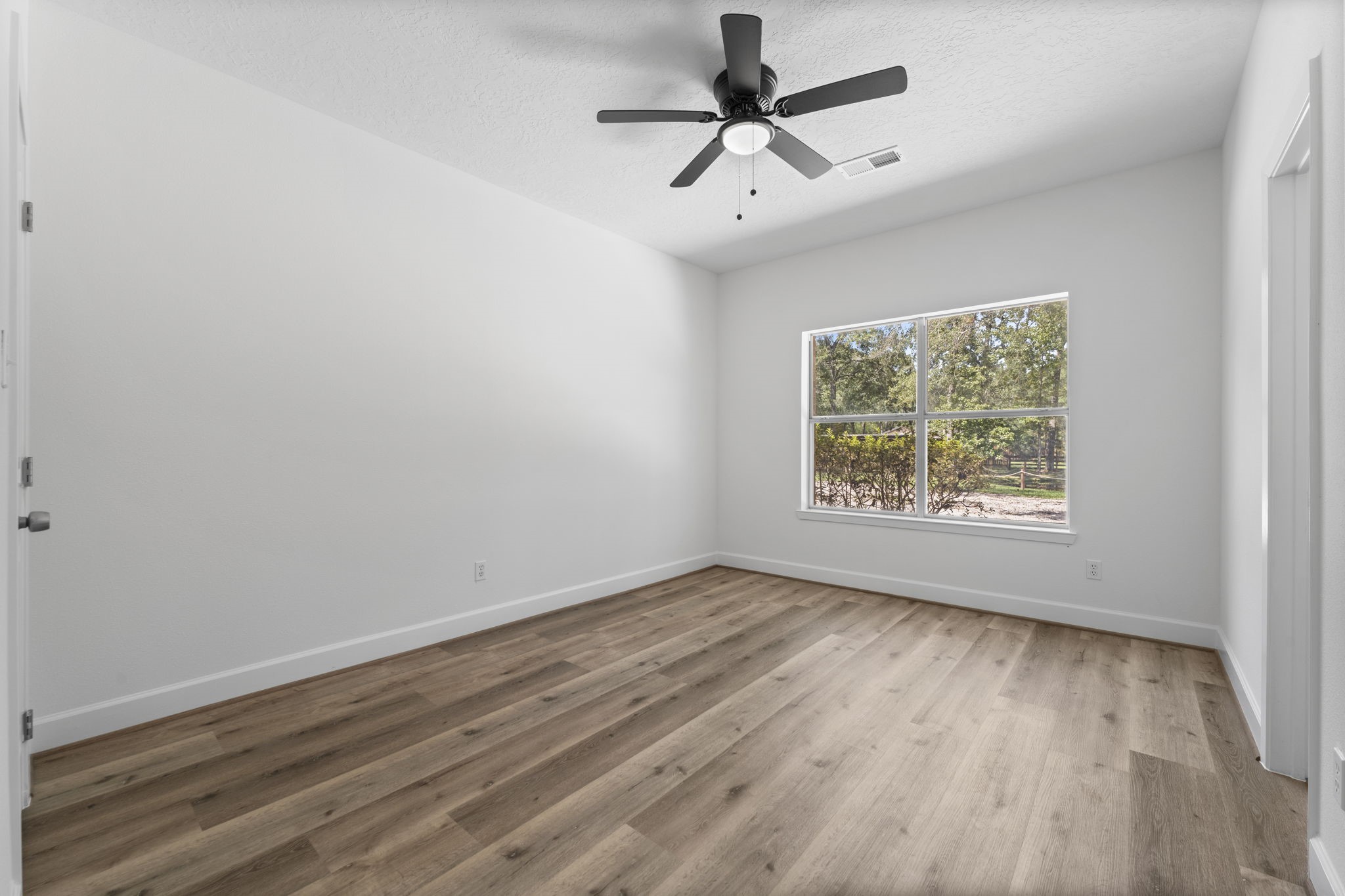 15456 Pin Oak Drive Conroe, TX 77384 - Photo 33 of 44 an empty room with wooden floor ceiling fan and windows