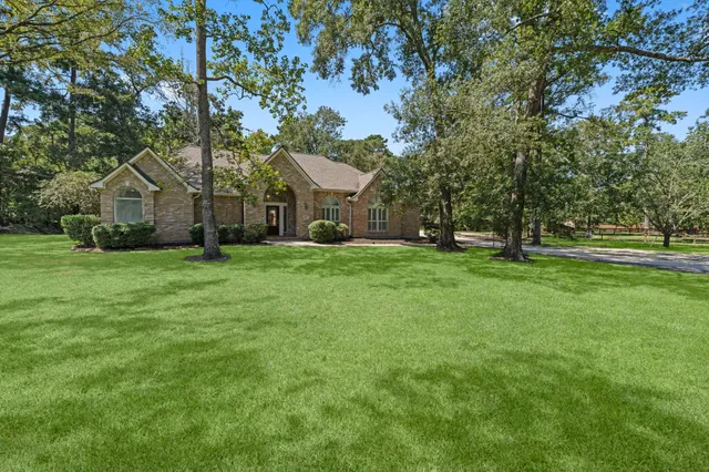 a view of a house with a big yard and large trees