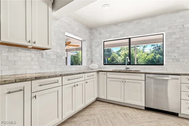 a kitchen with white cabinets and a large window