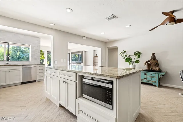a kitchen with granite countertop white cabinets and white appliances