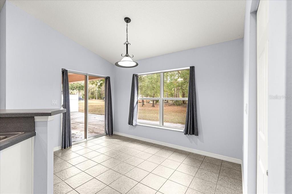 21595 Southwest 84th Loop Dunnellon, FL 34431 - Photo 17 of 62 a view of an empty room with window chandelier and a kitchen view