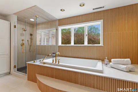 a bathroom with a tub a sink and a large mirror