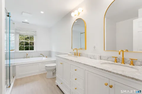 a bathroom with a granite countertop toilet a sink a mirror and bathtub