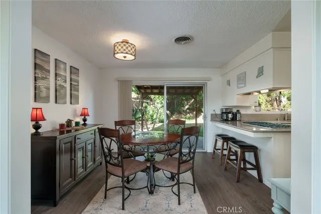 a view of a dining room and livingroom with furniture wooden floor a rug a potted plant and a chandelier