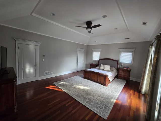 a bedroom with a bed and a dresser with wooden floor