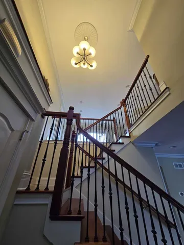 a view of staircase with railing and a chandelier