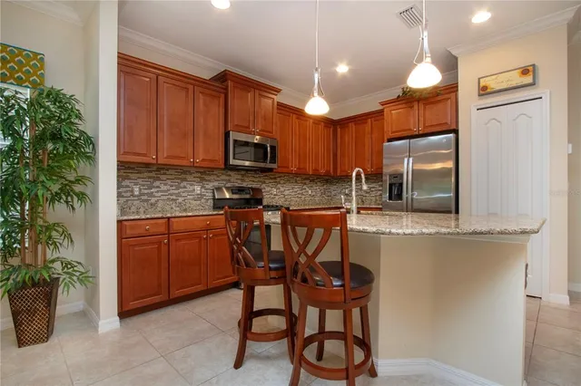 a kitchen with stainless steel appliances granite countertop wooden cabinets a sink a stove a refrigerator and a oven
