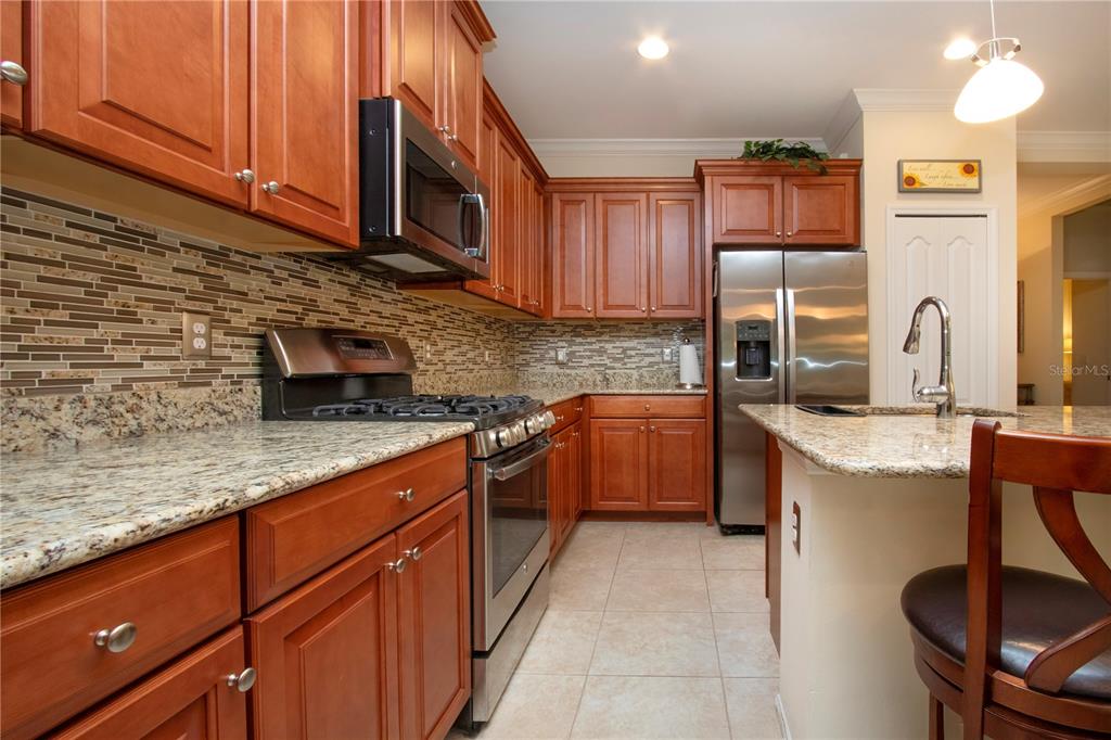 4920 Maymont Park Circle Bradenton, FL 34203 - Photo 31 of 59 a kitchen with stainless steel appliances granite countertop a sink a stove a refrigerator cabinets and chairs