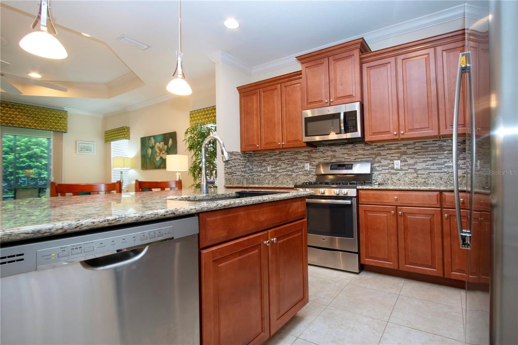 4920 Maymont Park Circle Bradenton, FL 34203 - Photo 33 of 59 a kitchen with stainless steel appliances granite countertop a sink stove and microwave