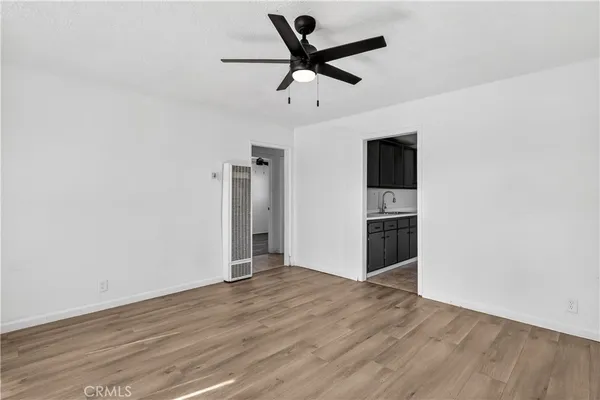 a view of a room with wooden floor a ceiling fan and windows