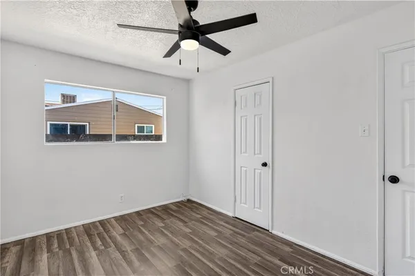 an empty room with wooden floor and ceiling fan
